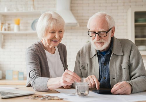 Grandparents putting coin into moneybox, economy for nest egg, pension, mortgage loan at home